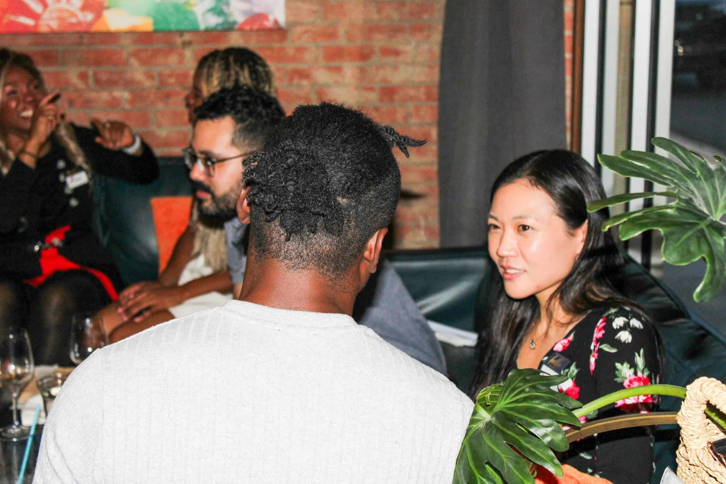 Members talking across a table in a brick-walled bar.