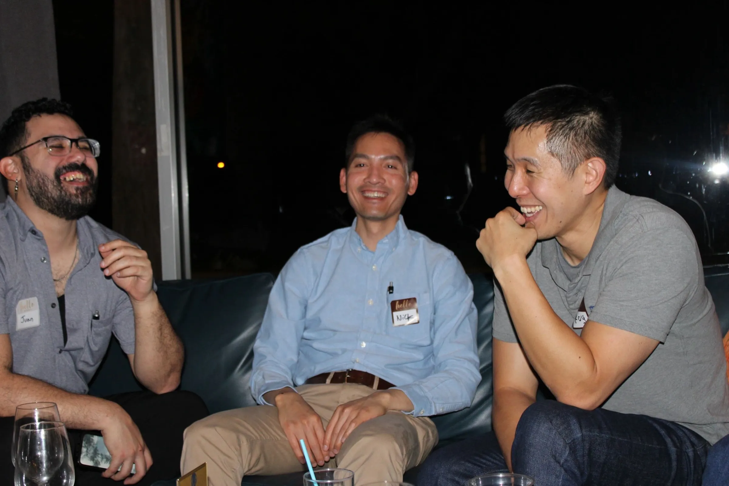 Three men laughing together on a couch.