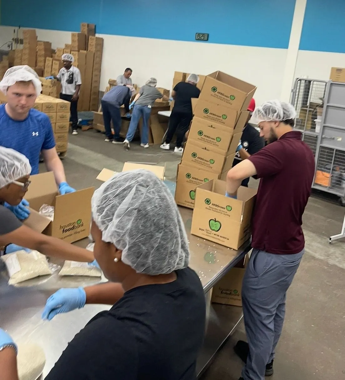 Volunteers in hairnets packing boxes at the Houston Food Bank.